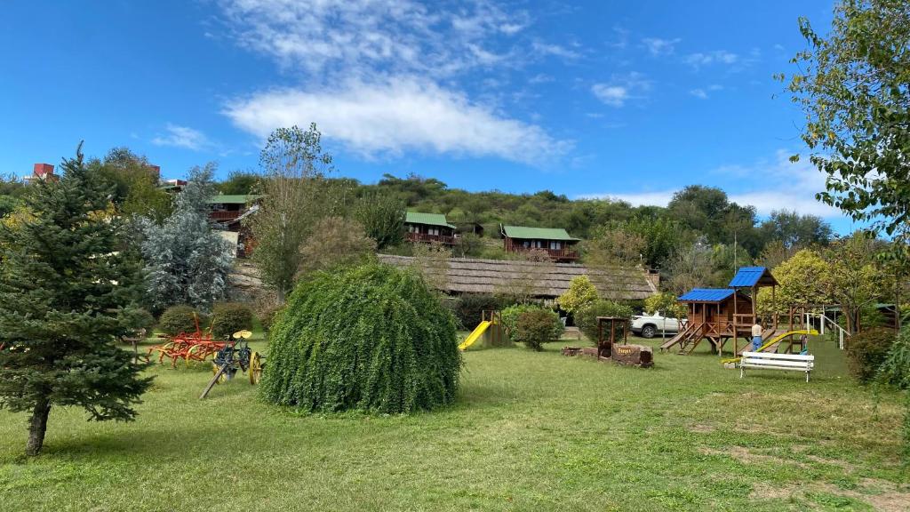 a yard with a playground and a house at Cabañas Ensueño in Villa Carlos Paz