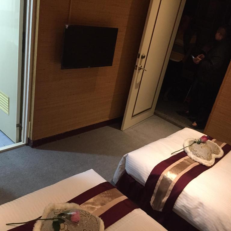 two beds in a room with a tv and a mirror at Gu-Ting-Ben B&amp;B in Minxiong