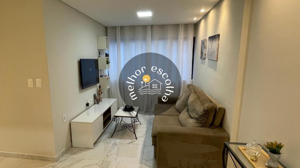 a living room with a couch and a sign at Apartamento completo a 200m da praia in Maceió