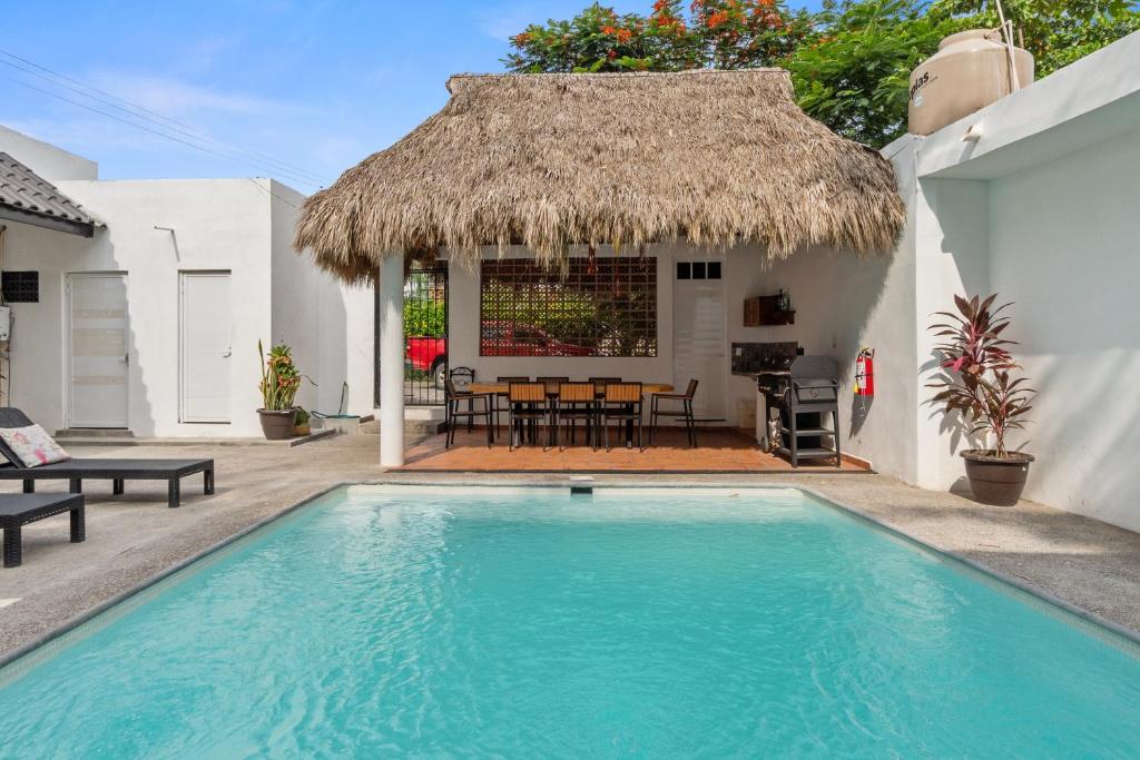 a villa with a swimming pool and a thatch roof at Casona Santa Rita Bucerias in Bucerías
