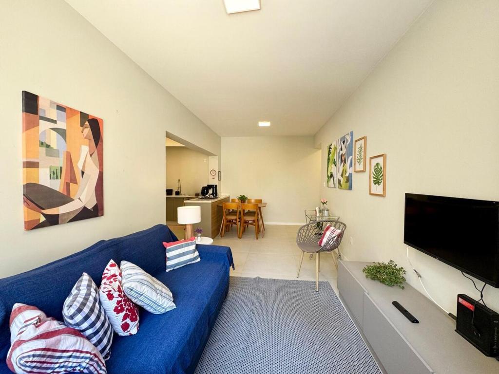 ein Wohnzimmer mit einem blauen Sofa und einem Flachbild-TV in der Unterkunft Apartamento no Centro - conforto e praticidade in Florianópolis