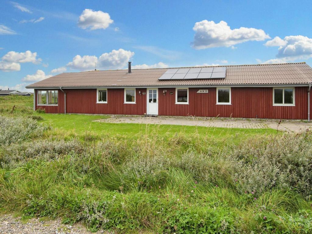 Un edificio rojo con techo solar en un campo. en 10 person holiday home in Harboøre-By Traum, en Harboør