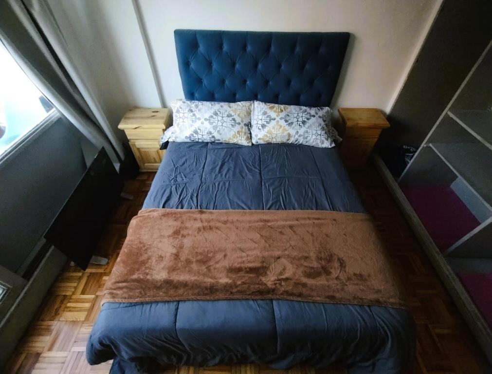 a bed with a blue headboard in a room at Central y Comodo Departamento in Buenos Aires