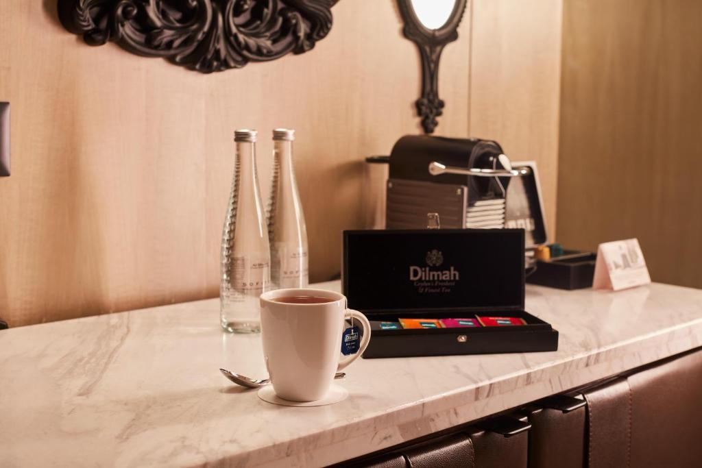 A marble-topped in-room coffee and work counter with a laptop, coffee, water and tea service.