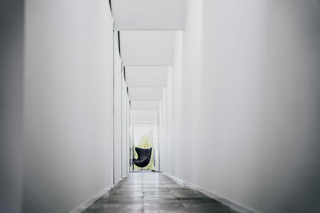 a hallway with a black chair in a white room at Alkina Lodge Namu in Wattle Hill