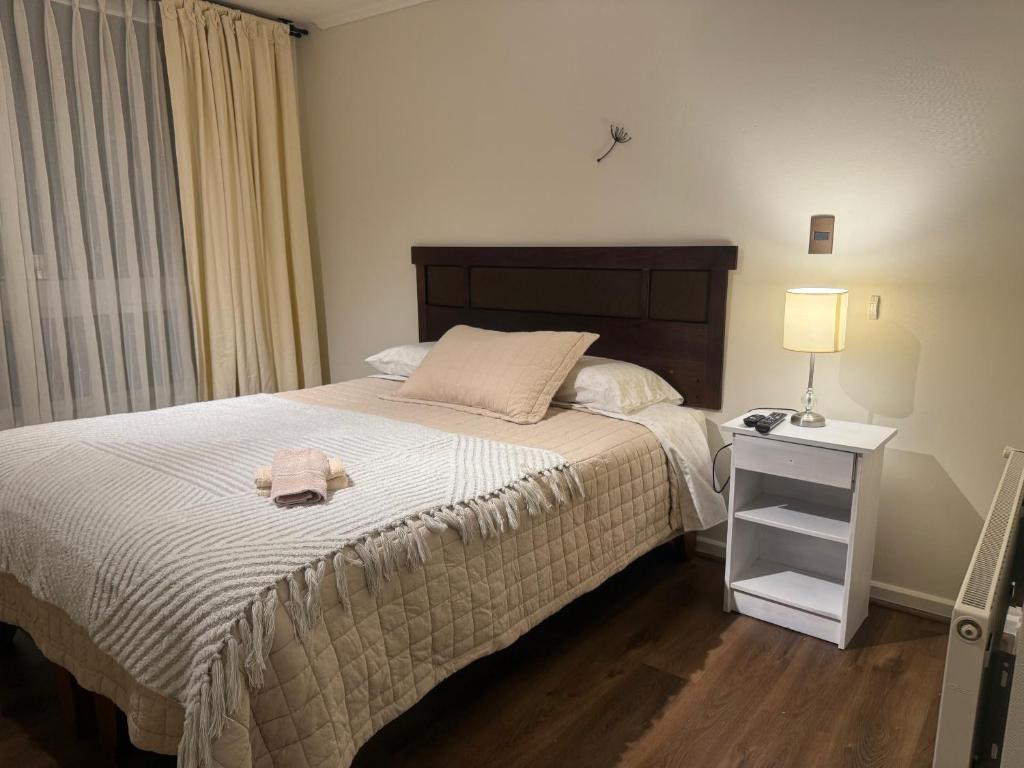 a bedroom with a bed and a table with a lamp at DPTO frente MALL-AEROPUERTO, CONCEPCION in Concepción
