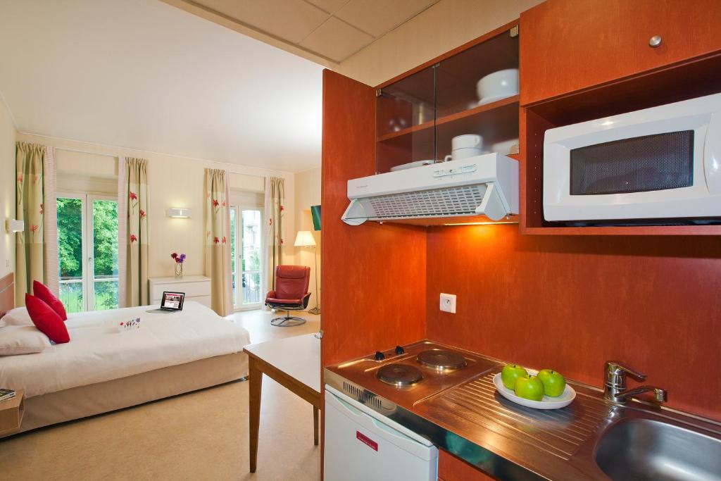 a room with a kitchen and a living room at Hotels &amp; Résidences - Les Thermes in Luxeuil-les-Bains