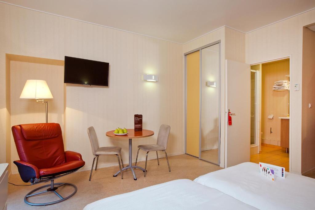 a hotel room with a table and chairs and a bed at Hotels &amp; Résidences - Les Thermes in Luxeuil-les-Bains