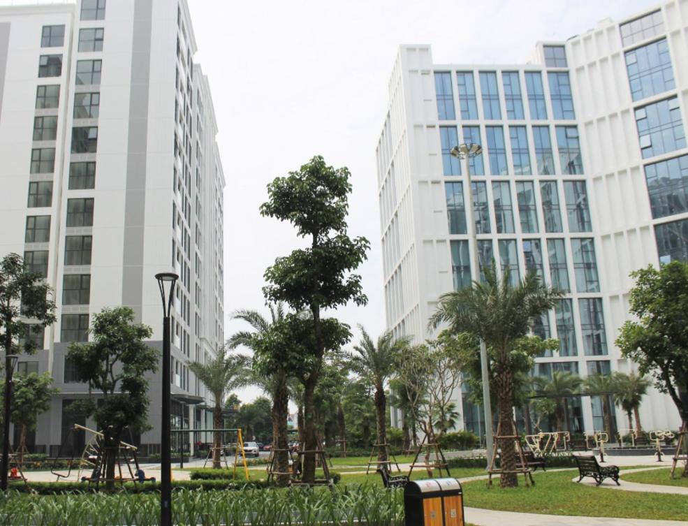 two tall buildings in a park with trees and benches at Bright modern haven in Hanoi