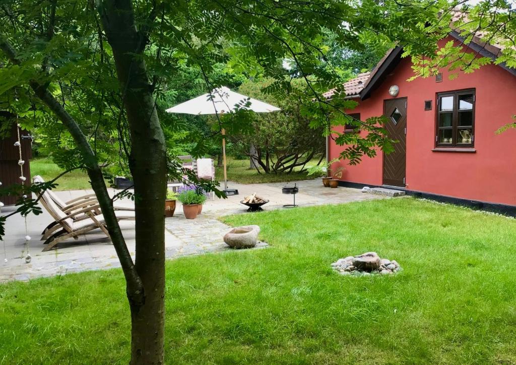 a garden with a red house and a lawn with a tree at Lovely Summerhouse By Sejerø Bay in Vig
