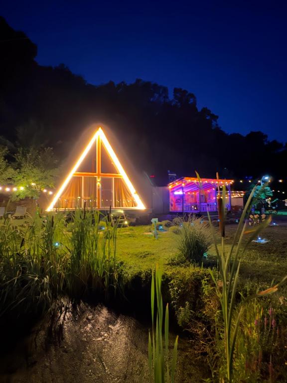 a greenhouse lit up at night with lights at Cabane A-Frame Svinița in Sviniţa