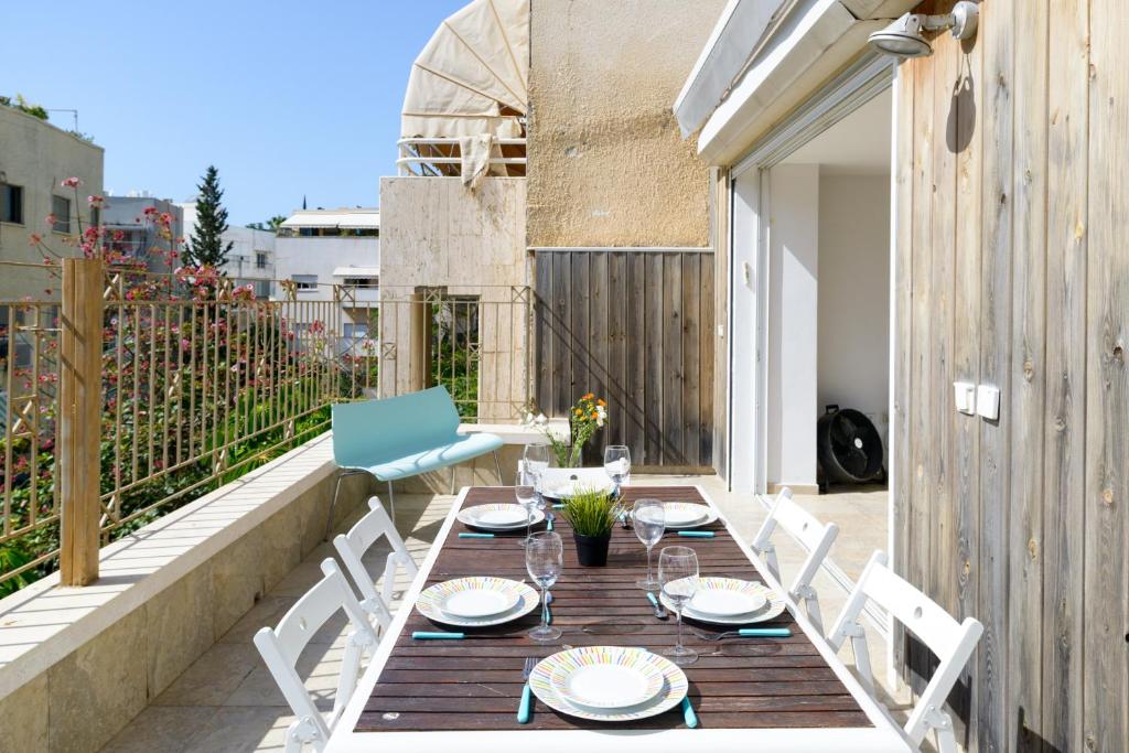 een houten tafel en witte stoelen op een patio bij Penthouse & Terrace near Hilton by FeelHome in Tel Aviv