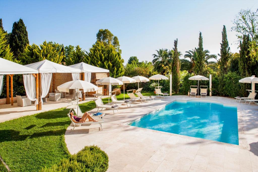 una piscina con tumbonas y sombrillas en Ostia Antica Park Hotel & Spa, en Ostia Antica