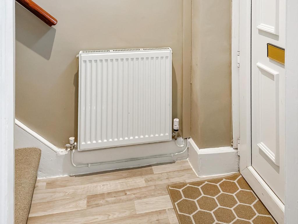 Un radiador blanco en una habitación al lado de una puerta. en The Bolt Hole, en Wooler