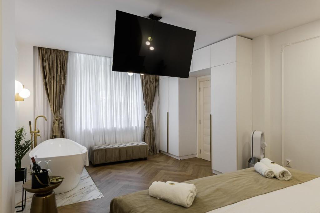 克卢日-纳波卡Eden Central Boutique Suites - Garden & Spacious Apartments的卧室里有浴缸，床上方有一台电视。