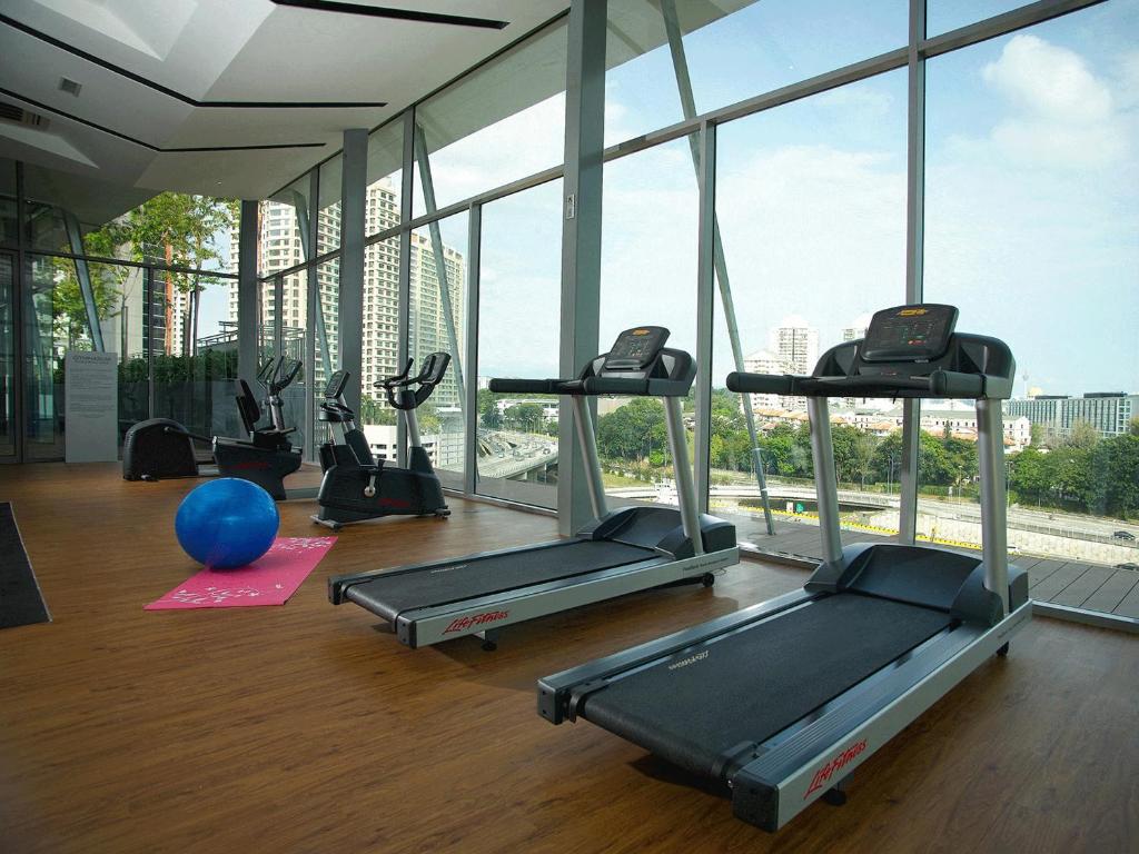 A bright, window-lined gym with treadmills and cardio equipment.
