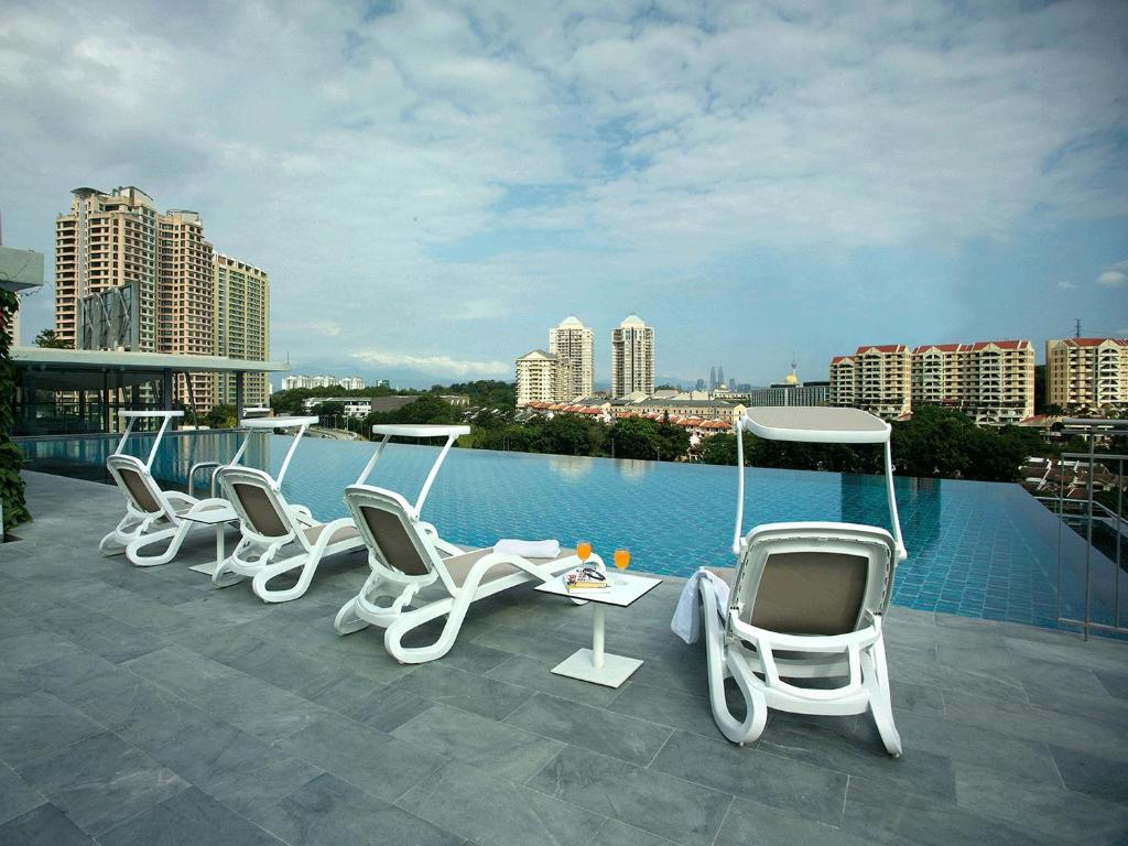 A rooftop pool terrace with loungers, a table, and skyline views.