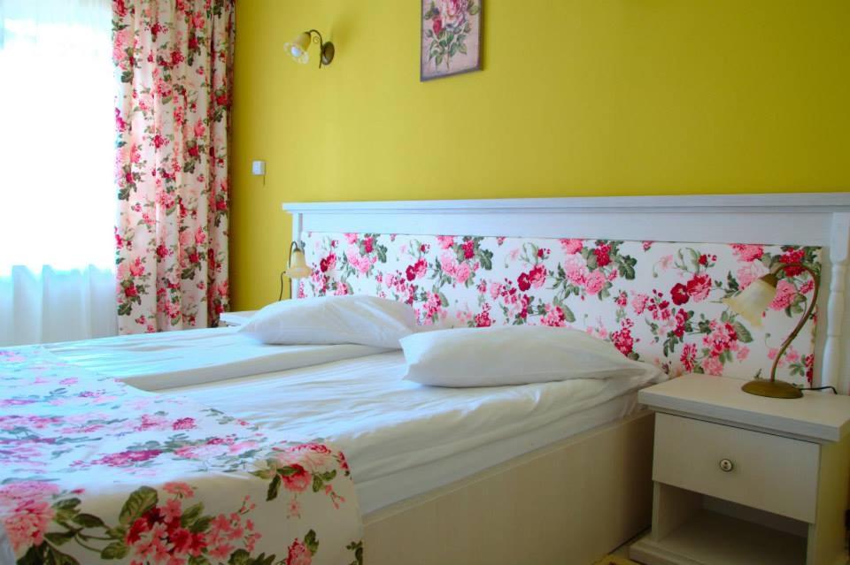 a bedroom with a white bed with a floral headboard at Pensiunea Cabana Soimul in Comăneşti