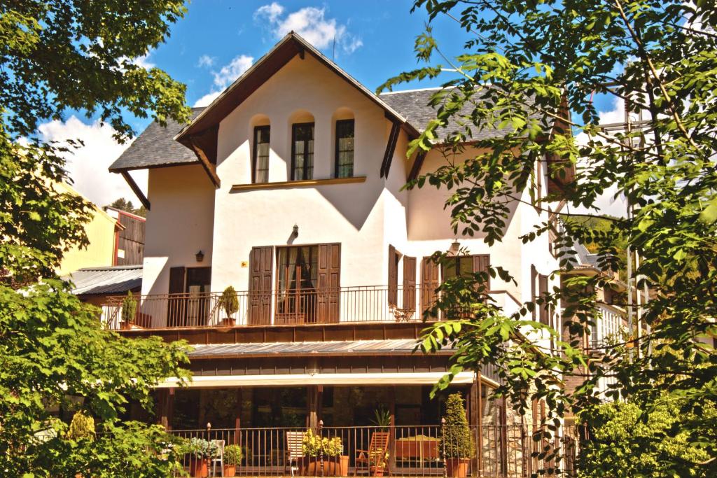 Großes weißes Haus mit Balkon in der Unterkunft Hotel Mas de Xaxas in Camprodon