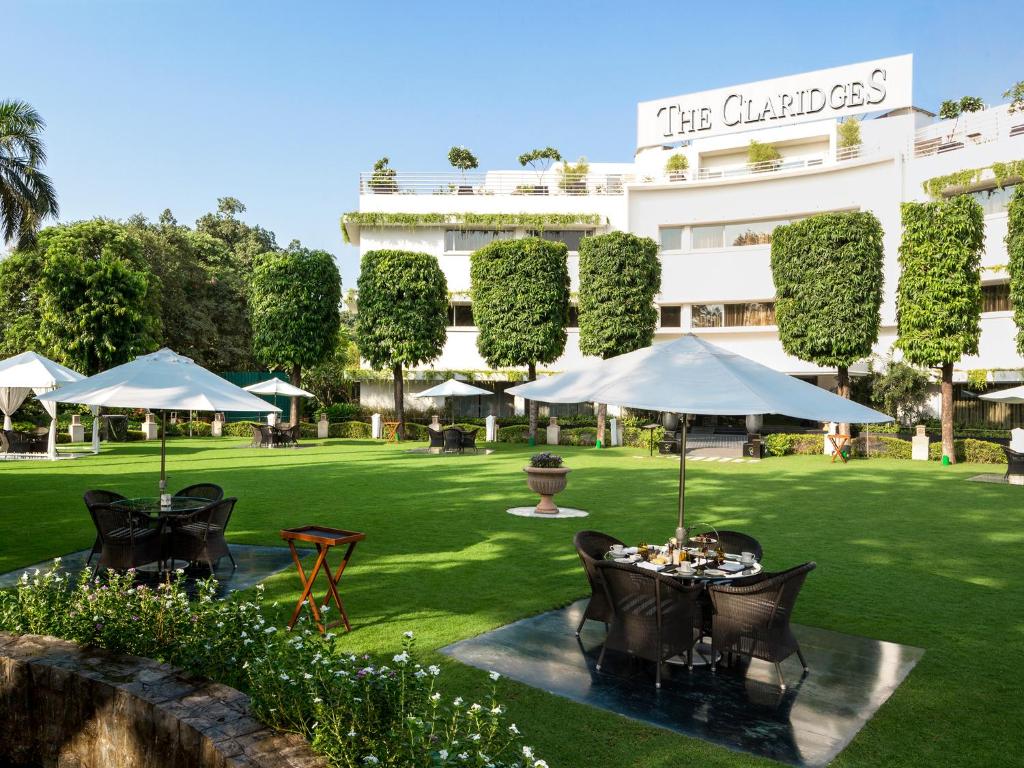 a patio area with tables, chairs and umbrellas at The Claridges New Delhi in New Delhi