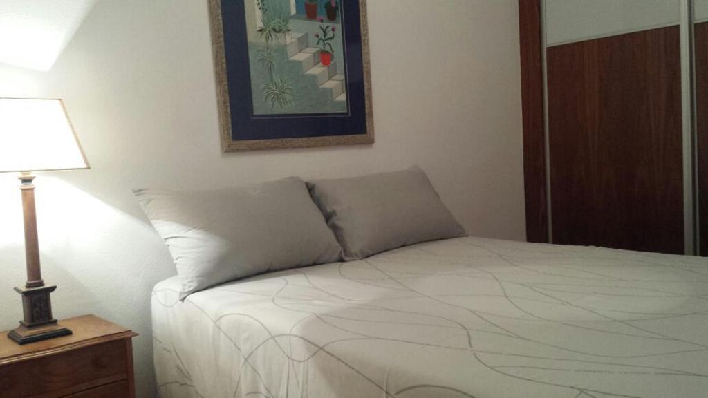 um quarto com uma cama e um candeeiro sobre uma mesa em PISO DE 3 HABITACIONES, CON GARAJE INCLUIDO, A 1500 metros de la CATEDRAL em Santiago de Compostela