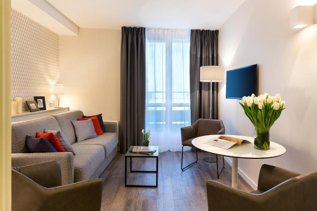 a living room with a couch and a table at Citadines Montmartre Paris in Paris