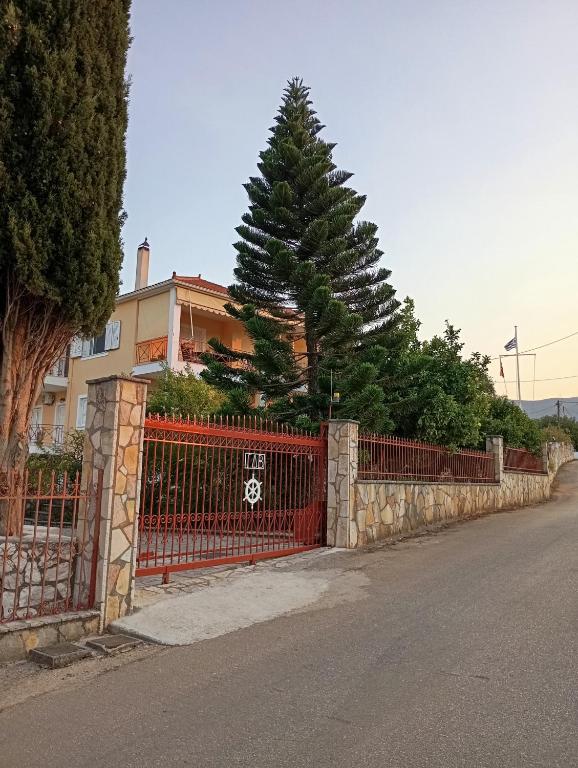 a red fence with a tree in front of a house at PENELOPE'S apartment in Kefalonia