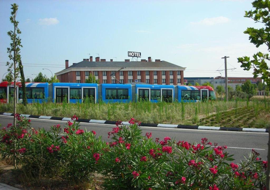 un treno blu su una strada accanto a un edificio di TH Boadilla a Boadilla del Monte