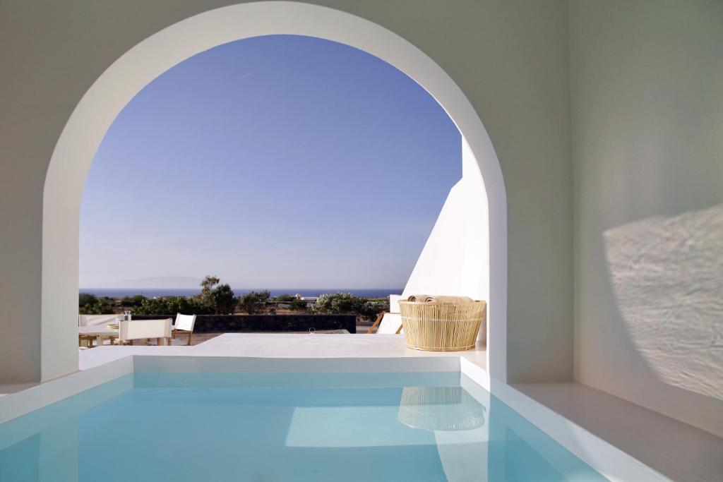 une arche au-dessus d'une piscine dans une maison dans l'établissement Vino Houses Santorini, à Oia