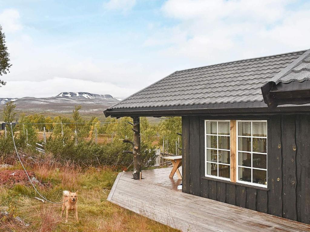 a small cabin with a dog standing on a deck at 4 star holiday home in Rennebu in Rennebu