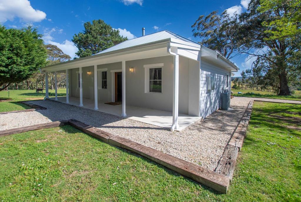 a small white house on a grass field at Cozy Cottage Blue Mountains in Lowther