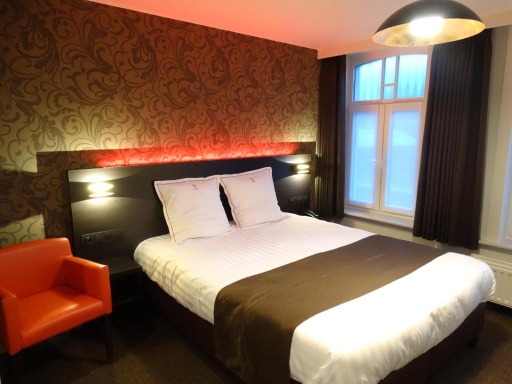 a hotel room with a bed and an orange chair at Hotel Kristoffel in Middelkerke
