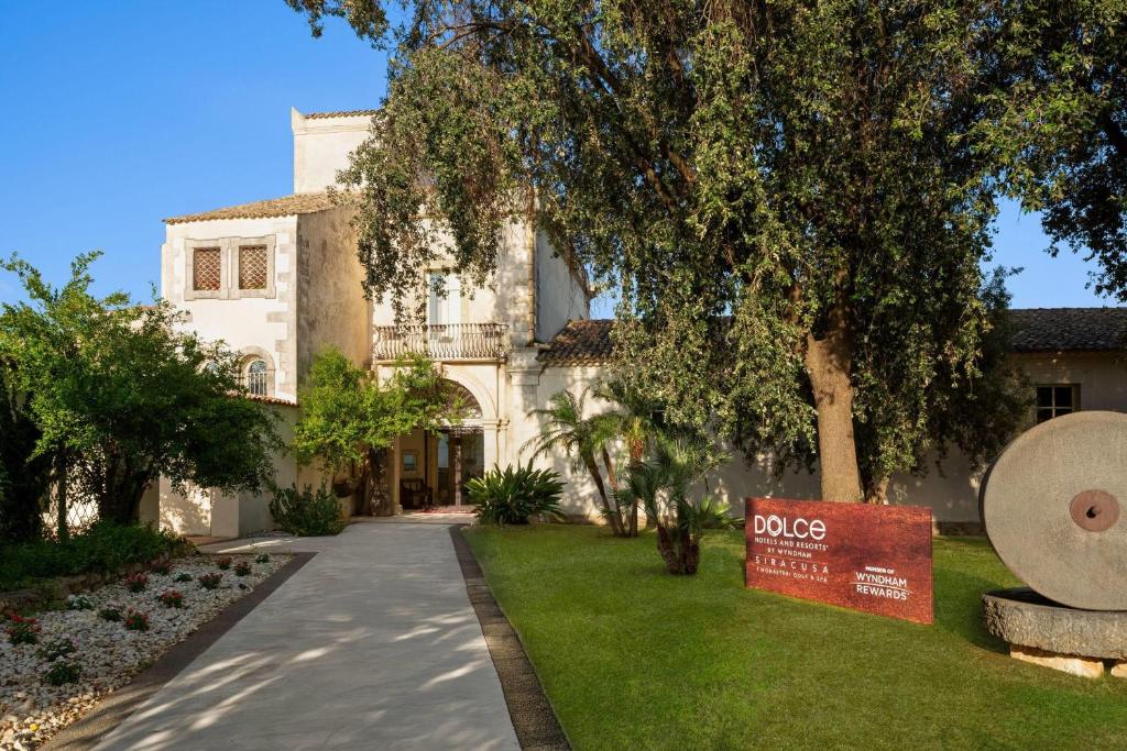 a building with a sign in front of a yard at Dolce by Wyndham Siracusa - I Monasteri Golf & Spa in Siracusa