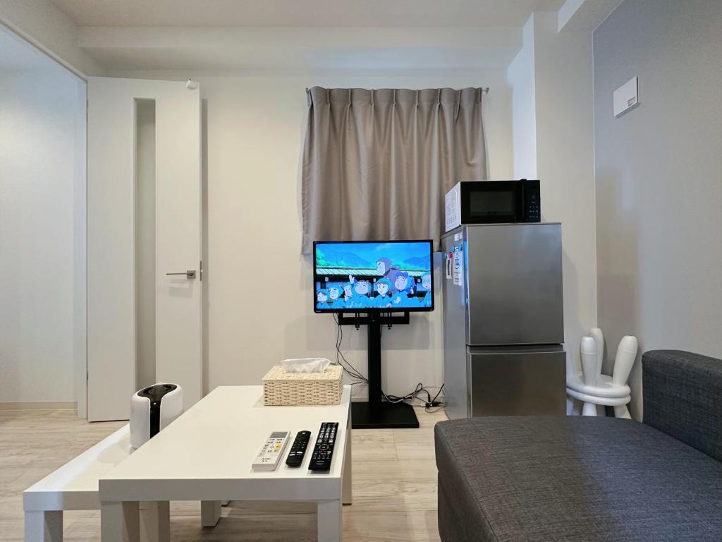 a living room with a flat screen tv and a couch at W-inns Asakusabashi in Tokyo