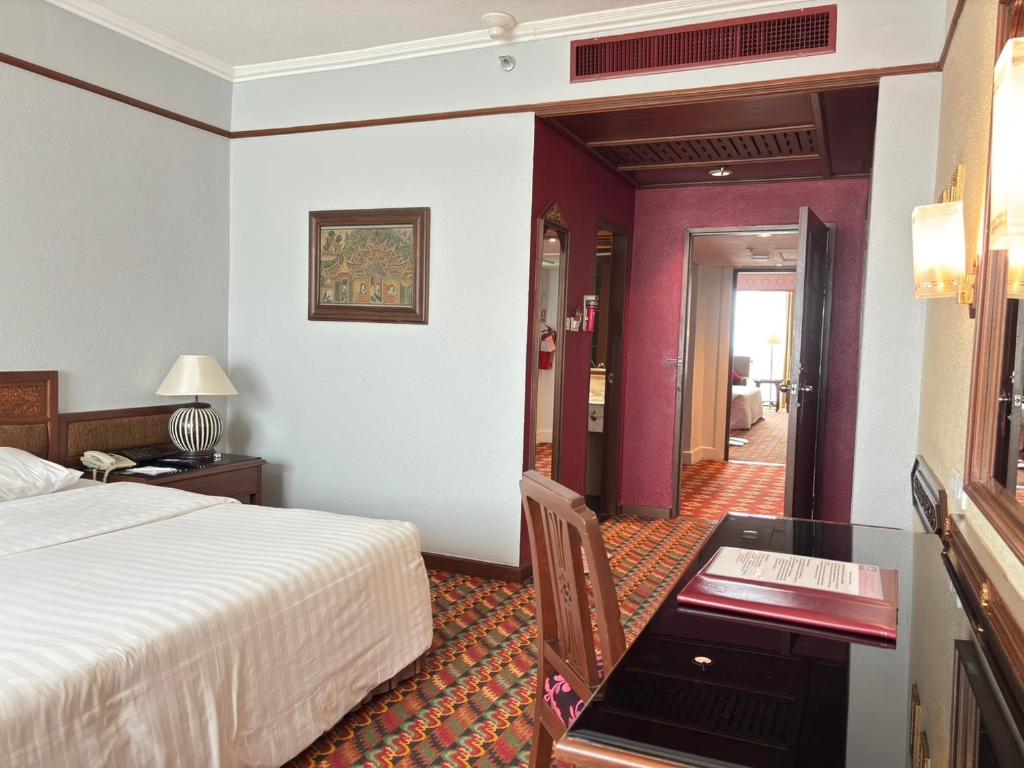 A bedroom with a writing desk opens onto a wood-trimmed hallway leading toward the entry area.