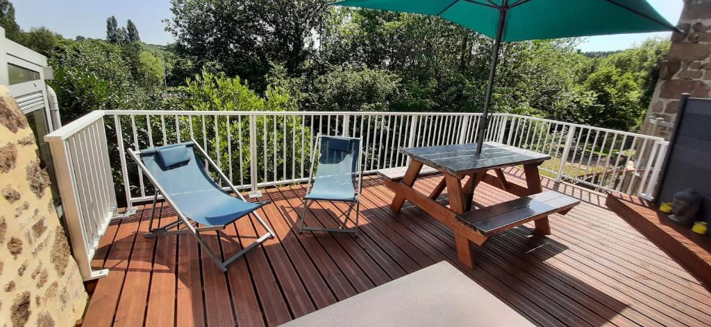 a wooden deck with a table and chairs and an umbrella at La Péra in Putanges