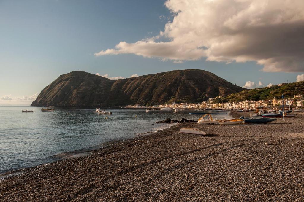 a beach with boats on the water and a mountain at Eolcalandra Case Per Vacanza in Canneto