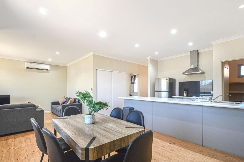 a kitchen and living room with a wooden table and chairs at Terrific Townhouse 3x2 in CBD in Port Hedland