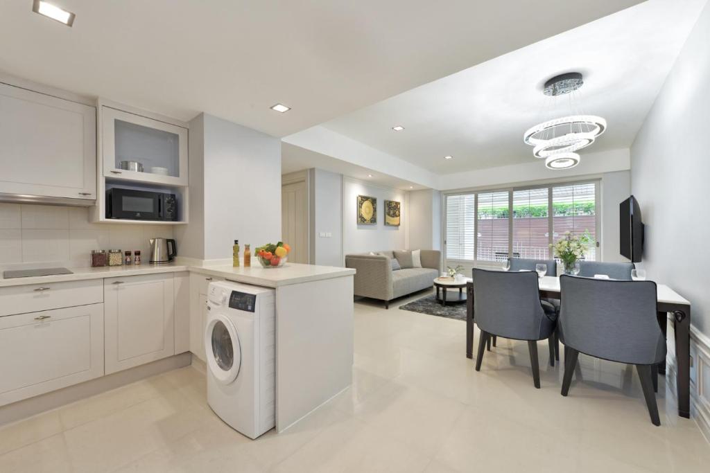 An open-plan apartment-style interior combining a kitchen, dining area, living room, and laundry machine.