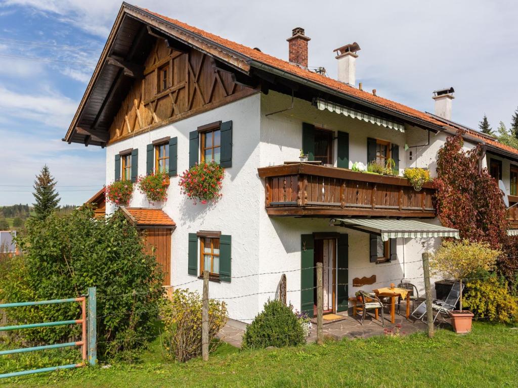 a white house with a wooden roof at Alpenapartment mit Garten in Trauchgau