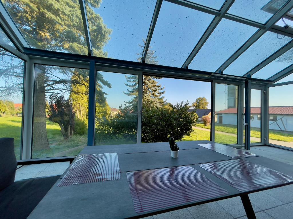 a glass house with a table in front of windows at Hesselberg-Oase Ferienhof Hüttner in Röckingen