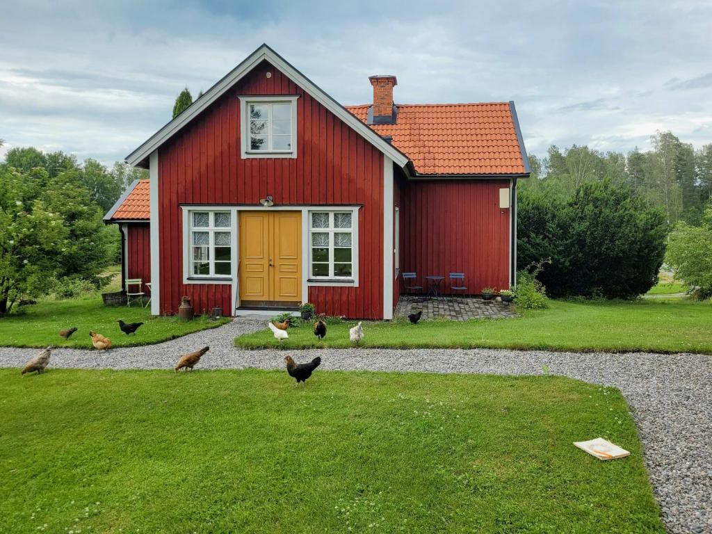 a red house with chickens standing outside of it at Rural 19Th Century House Near Götlunda in Arboga