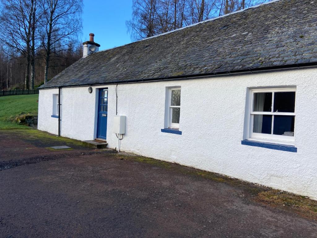 un bâtiment blanc avec une porte et des fenêtres bleues dans l'établissement Fordie West Cottage, à Comrie