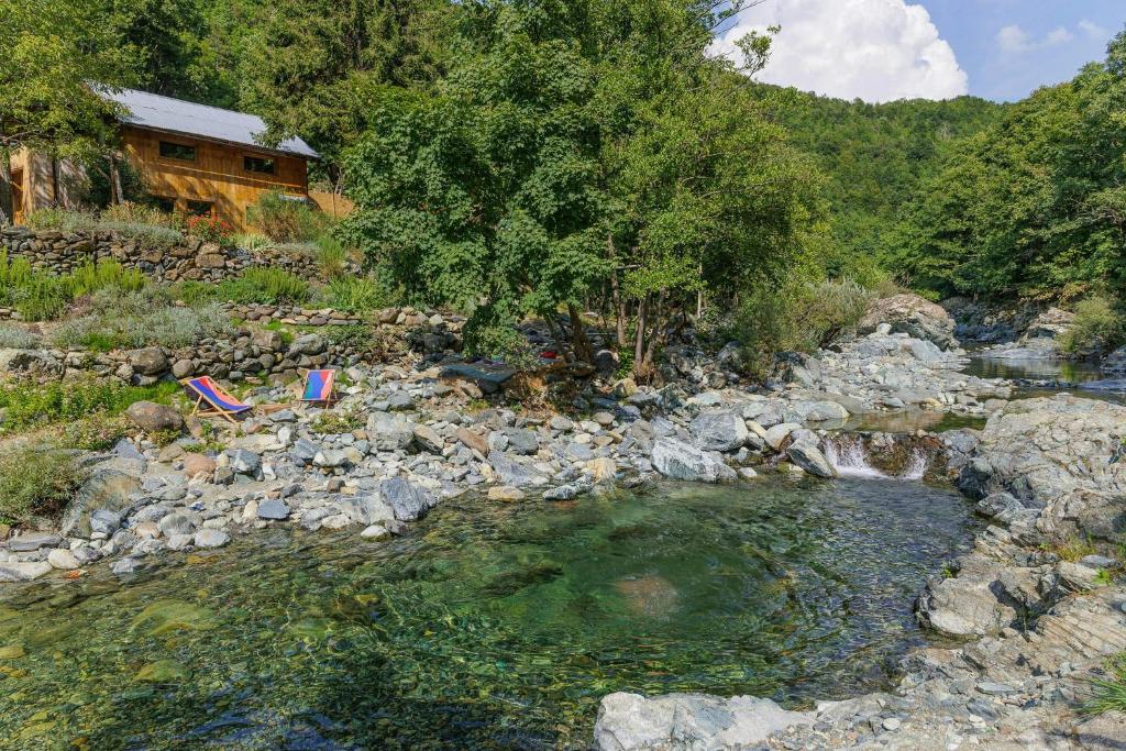 a river with two chairs sitting on the rocks at Natural Riverside Retreat In Tiglieto in Tiglieto