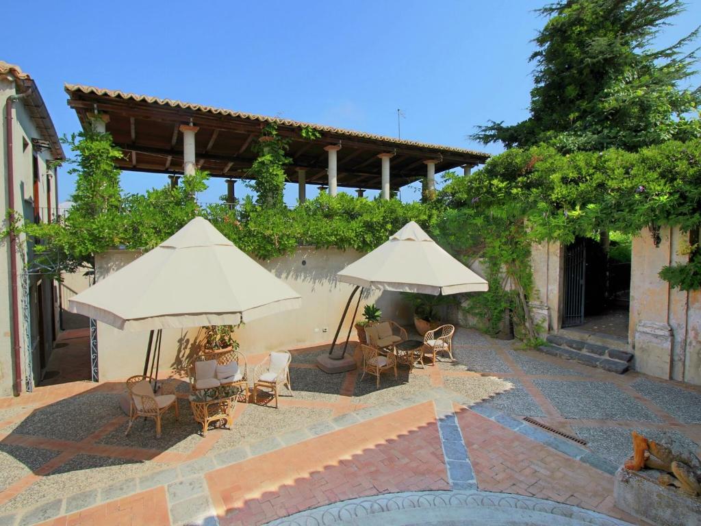 a patio with tables and chairs and umbrellas at Spacious Mansion in Parghelia near Sea in Parghelia