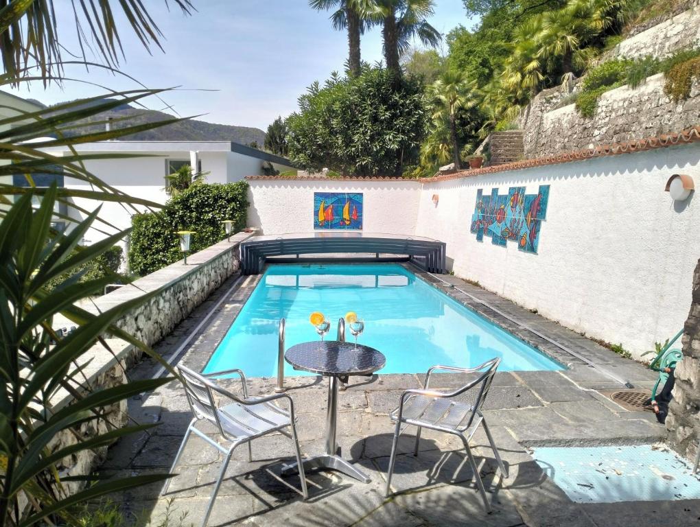 a swimming pool with a table and chairs next to a house at Villa Caslano in Caslano