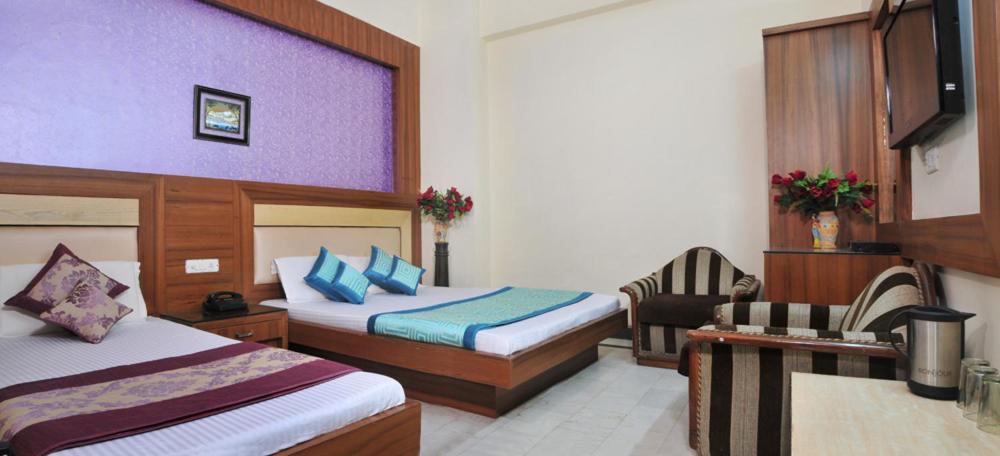 a hotel room with two beds and a chair at Hotel Star Paradise in New Delhi