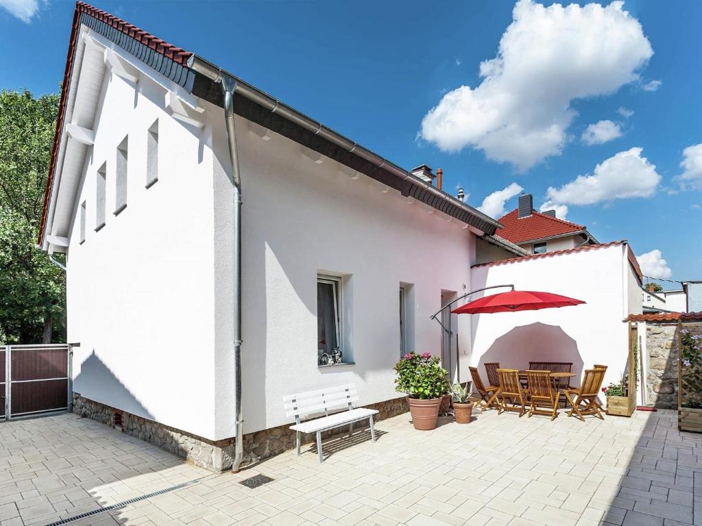 a white house with a patio with a red umbrella at Bright apartment in Thale with terrace in Thale
