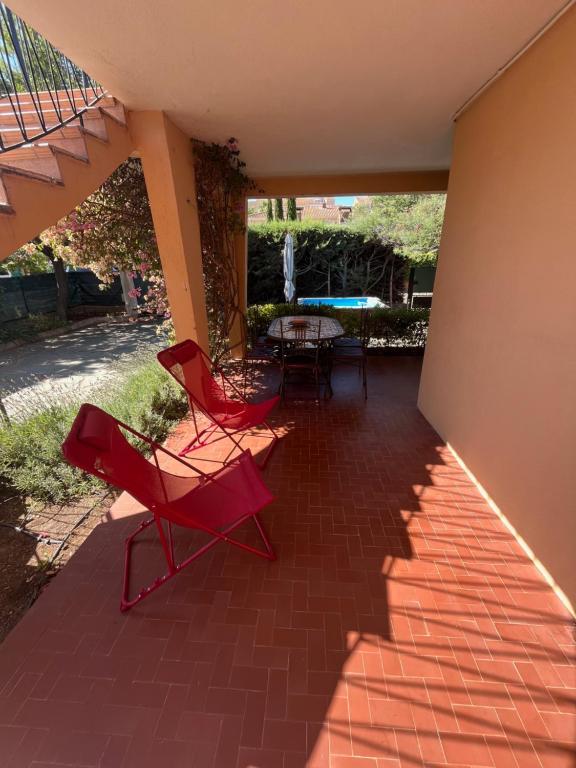 a patio with red chairs and a table on a brick floor at villa Kerlaf in Fréjus