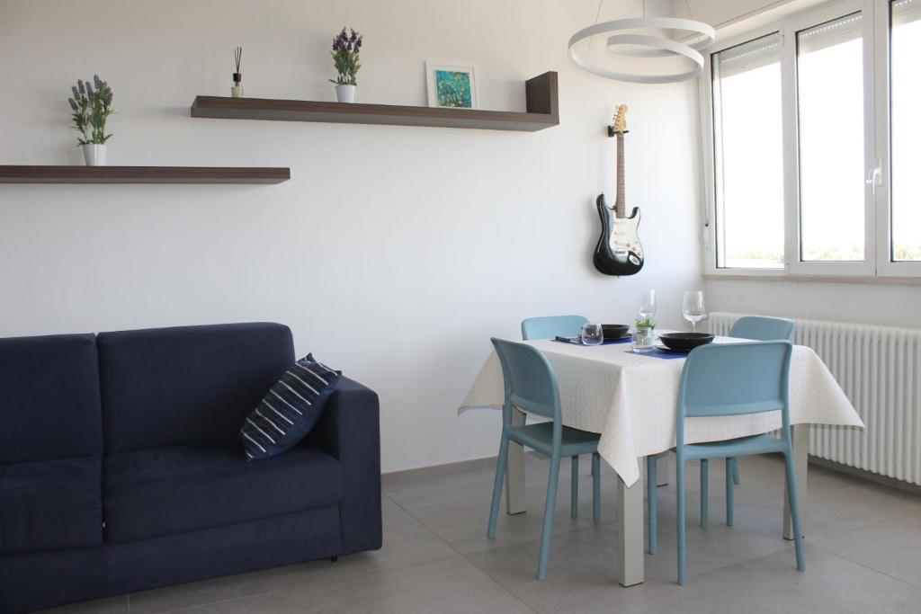 Un comedor con una mesa y sillas y un sofá. en NEWTON30 - Luminoso bilocale in zona servita, en Rávena